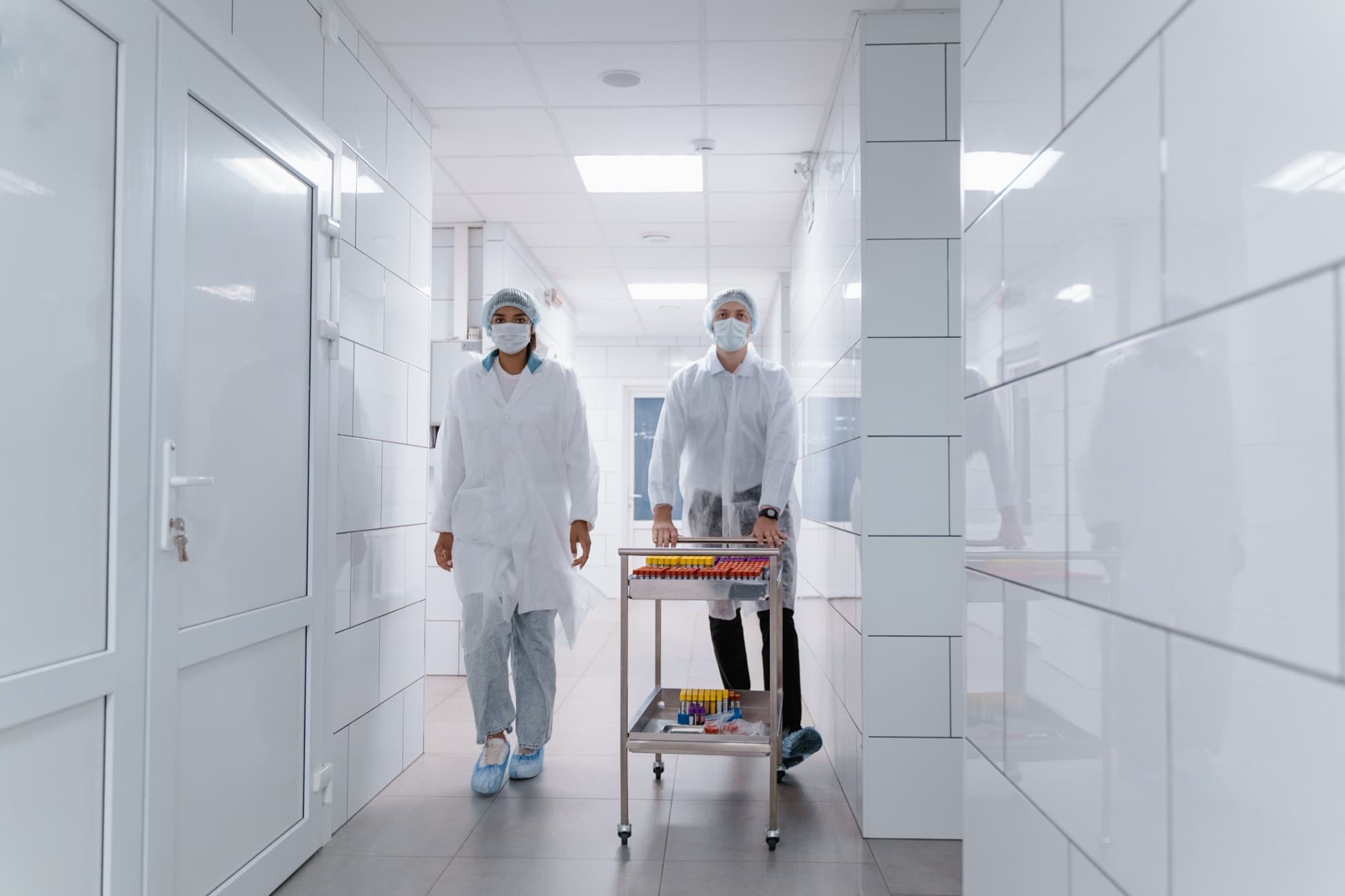Laboratory professionals moving supplies through a clinical corridor